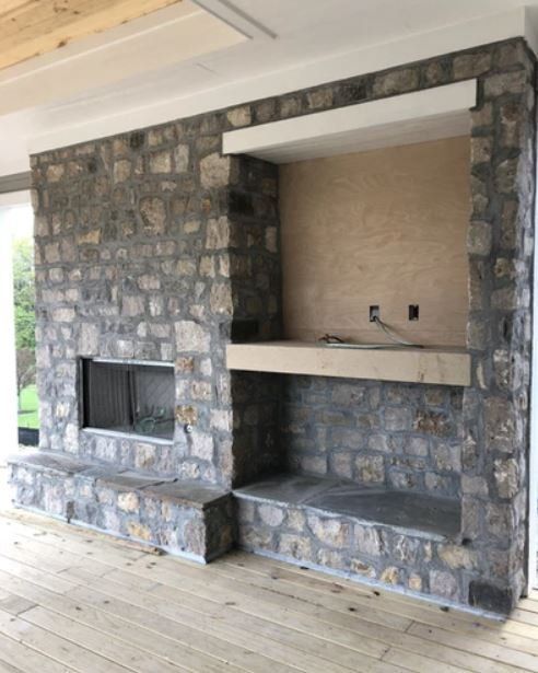 Stone fireplace with built-in shelves and a mantel in a room under construction