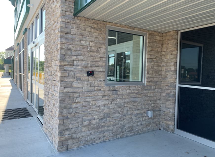 Stone building exterior with storefront windows and a covered entrance walkway
