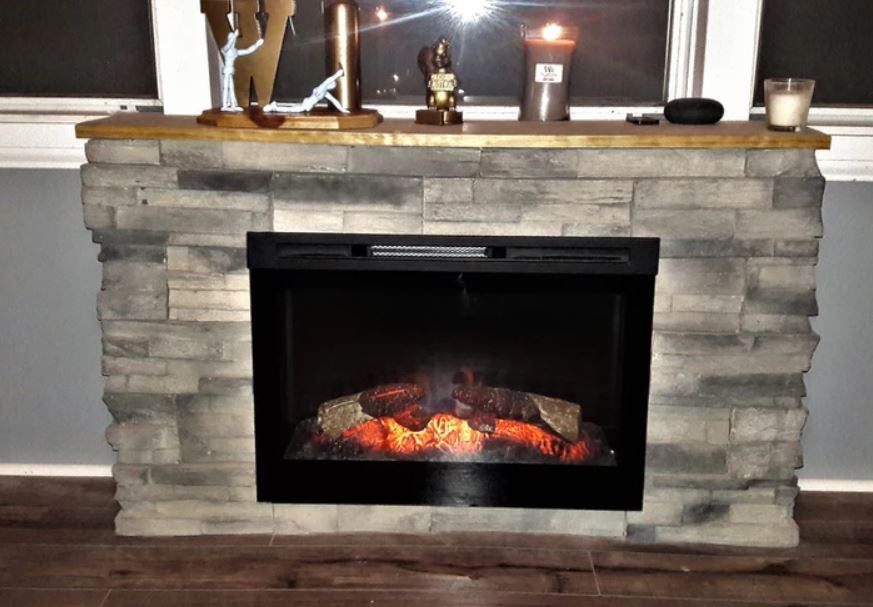 Stone fireplace mantel with decorative items and an electric fire burning inside