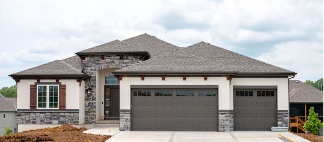 Modern single-story house exterior with stone accents, gray roof, and three-car garage