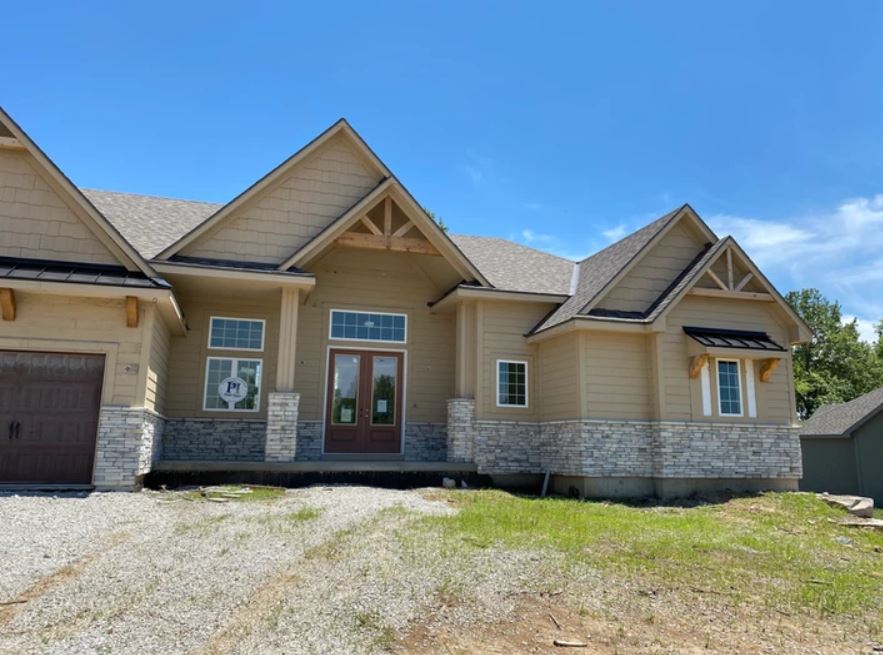 New beige suburban house with stone accents and a double garage under a blue sky