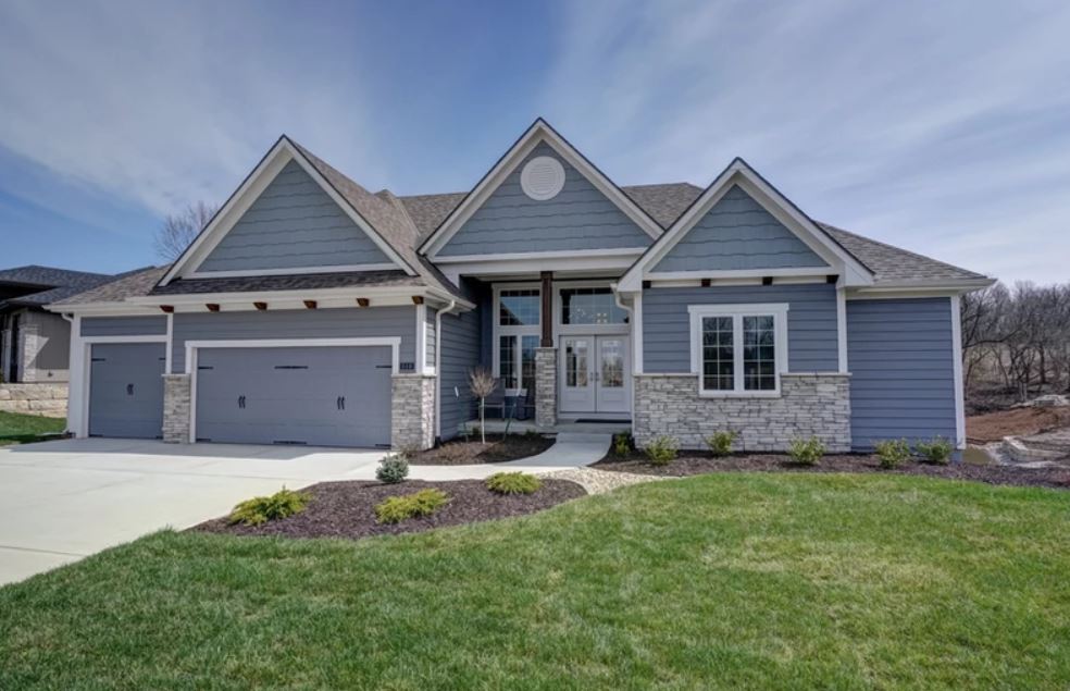 Front view of a gray suburban house with a two-car garage and manicured lawn