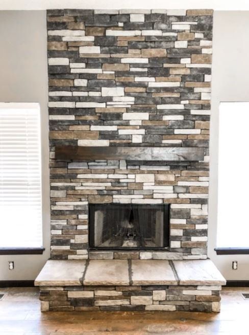 Stone fireplace with a dark brick surround and a raised hearth in a bright room