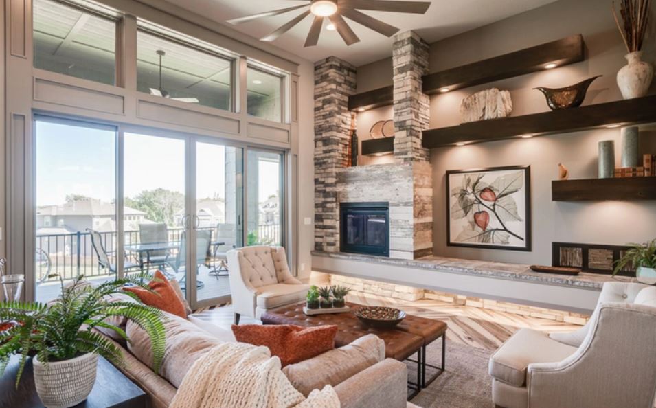 Bright modern living room with fireplace, large windows, and neutral furniture with blue accents