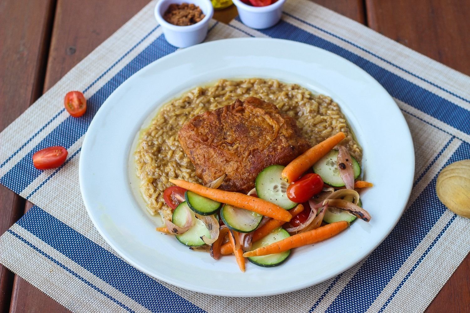 Plate of food: breaded patty on grain with sauteed vegetables.