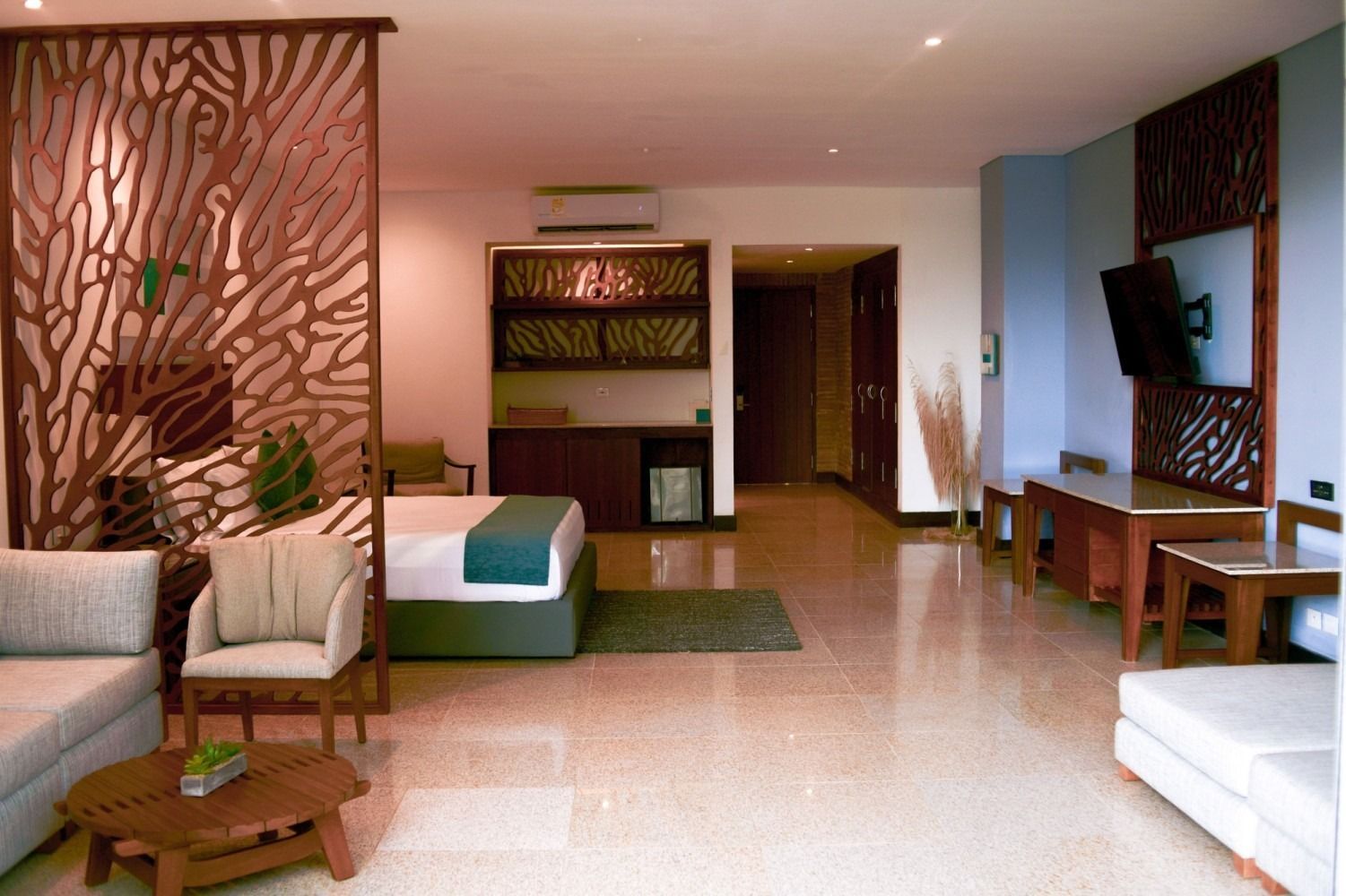 Spacious hotel suite with a modern design, wood accents, and light-colored furniture.