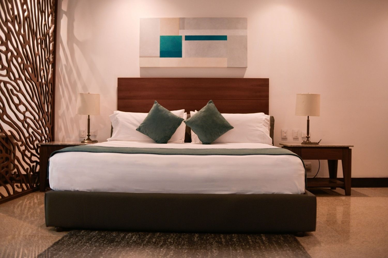 Bedroom with a bed, nightstands, lamps, artwork, and a decorative wall.
