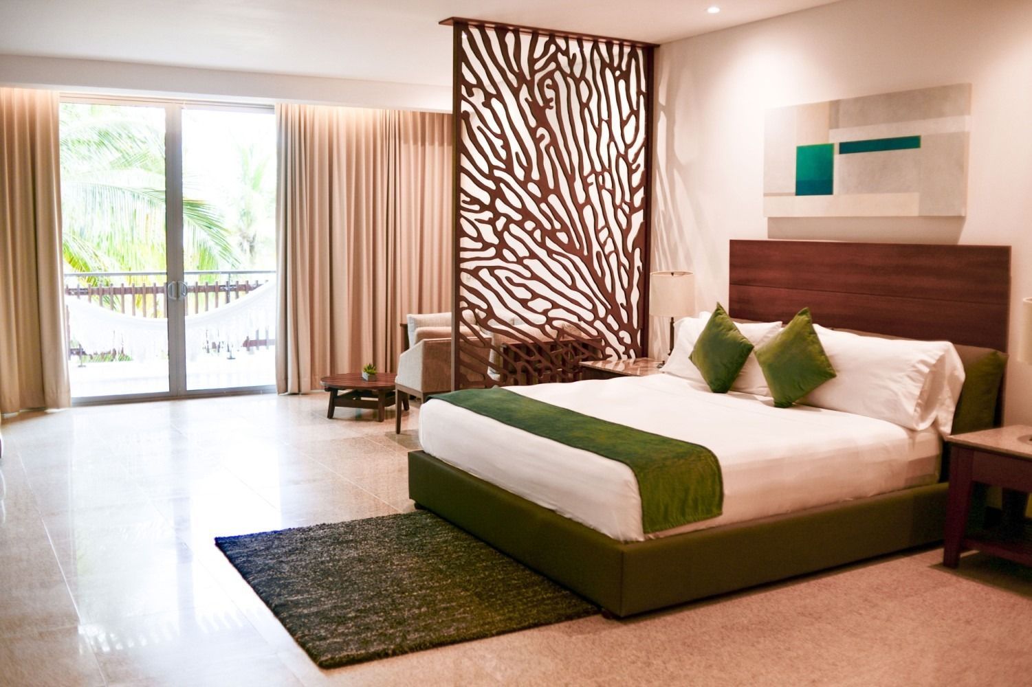 Spacious hotel room with a large bed, decorative wood screen, and outdoor access.
