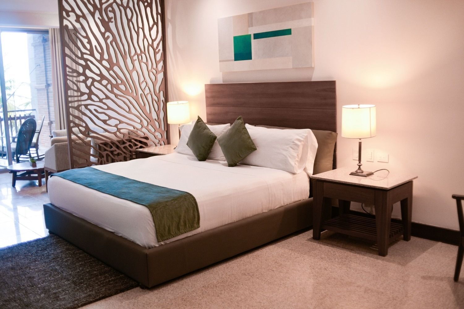 Bedroom with a bed, lamps, nightstand, and decorative screen.