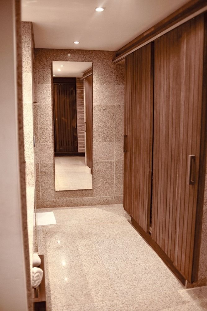 A narrow hallway with a full-length mirror, closet, and stone tile flooring.