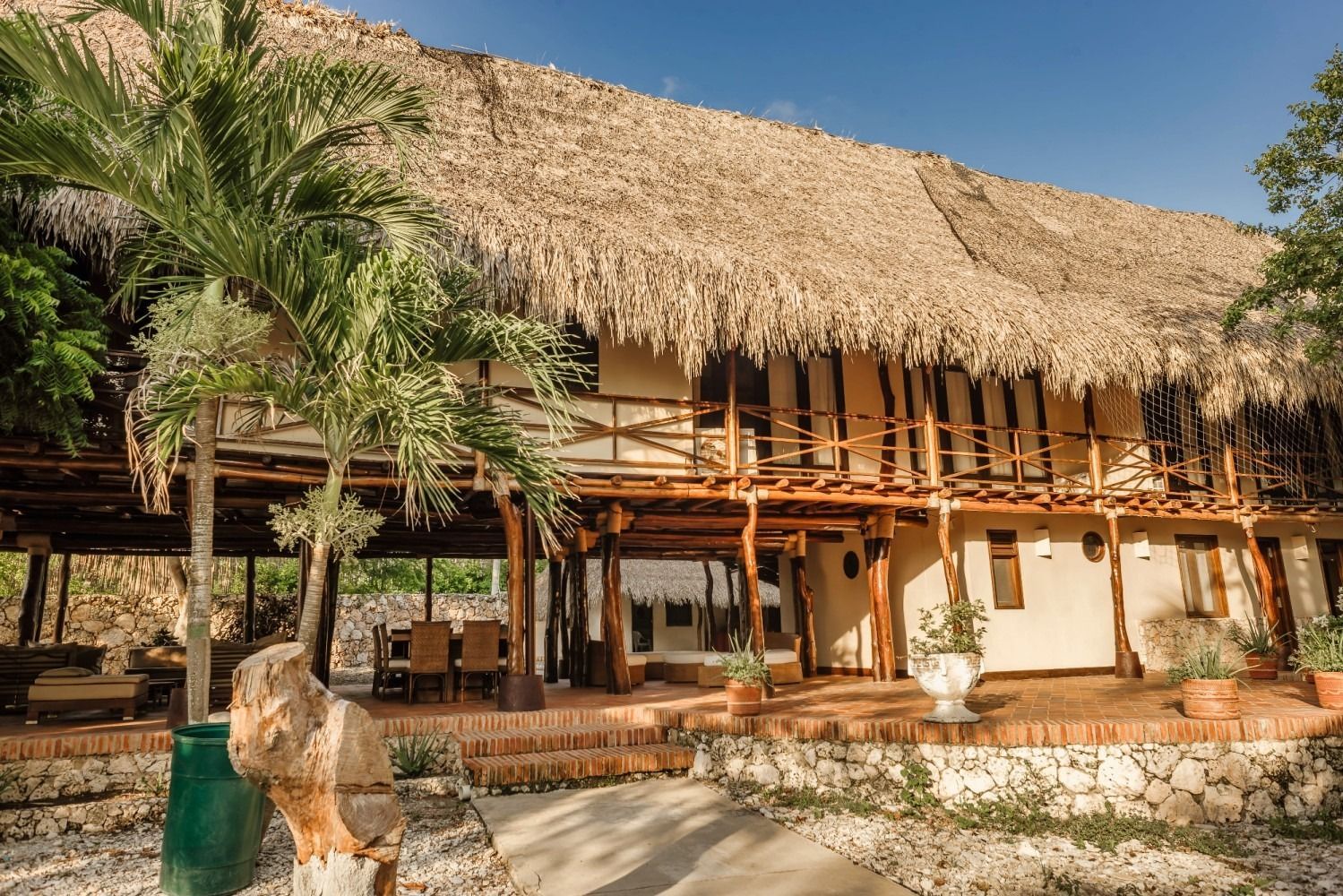 Two-story building with a thatched roof and balcony, outdoors, sunny.