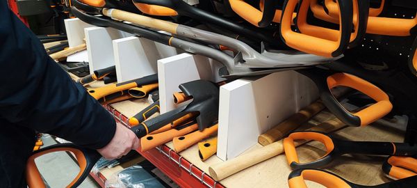 Person reaching for a shovel with an orange handle in a store display. Person reaching for a shovel with an orange handle in a store display.