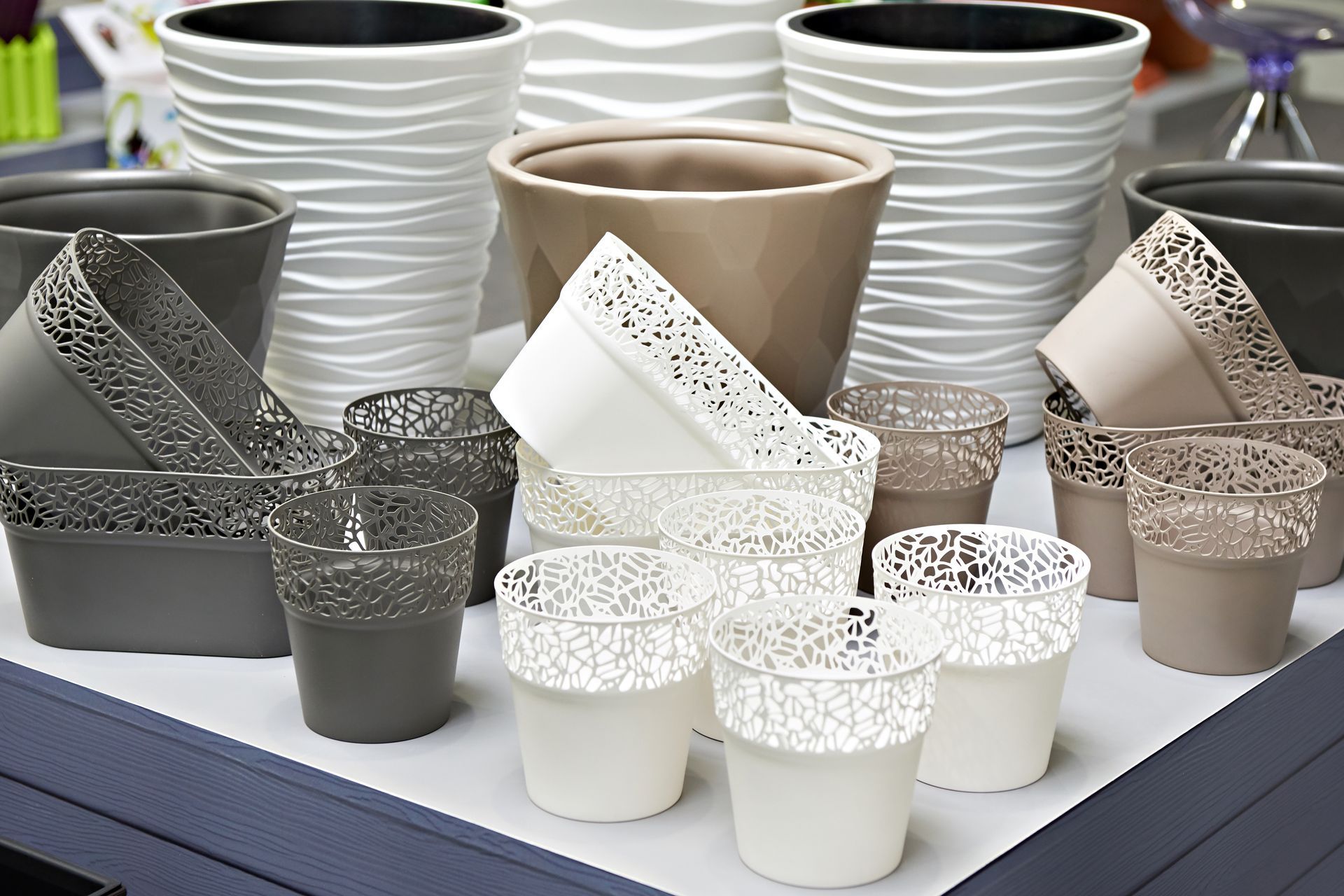 Flower pots in various sizes and colors, including white, gray, and beige. Some feature decorative patterns. Flower pots in various sizes and colors, including white, gray, and beige. Some feature decorative patterns.