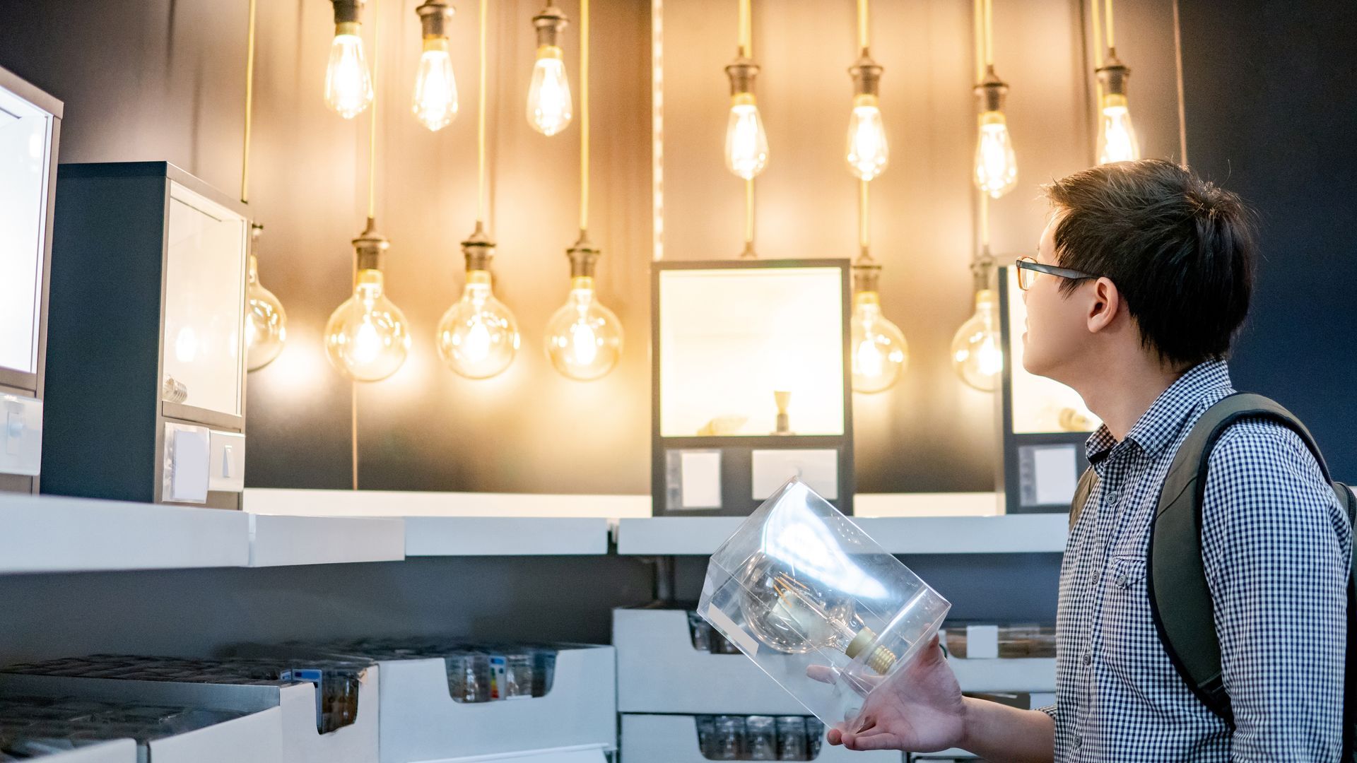 Man in glasses looks at display case with lights and a model inside. Man in glasses looks at display case with lights and a model inside.