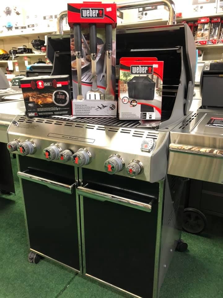Black metal barbecues on wheels displayed in a store. Black metal barbecues on wheels displayed in a store.