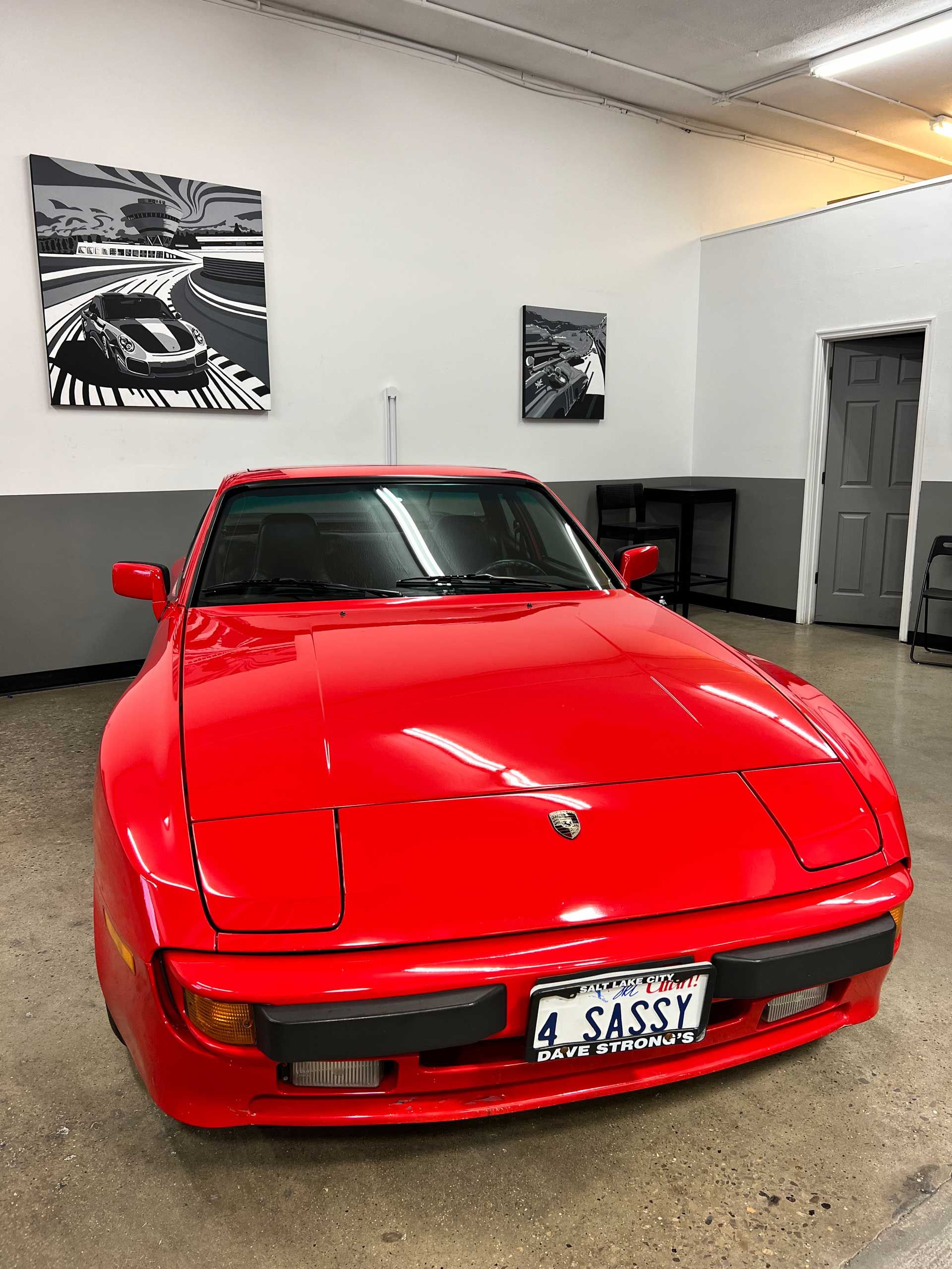 A red porsche 944 is parked in a garage.