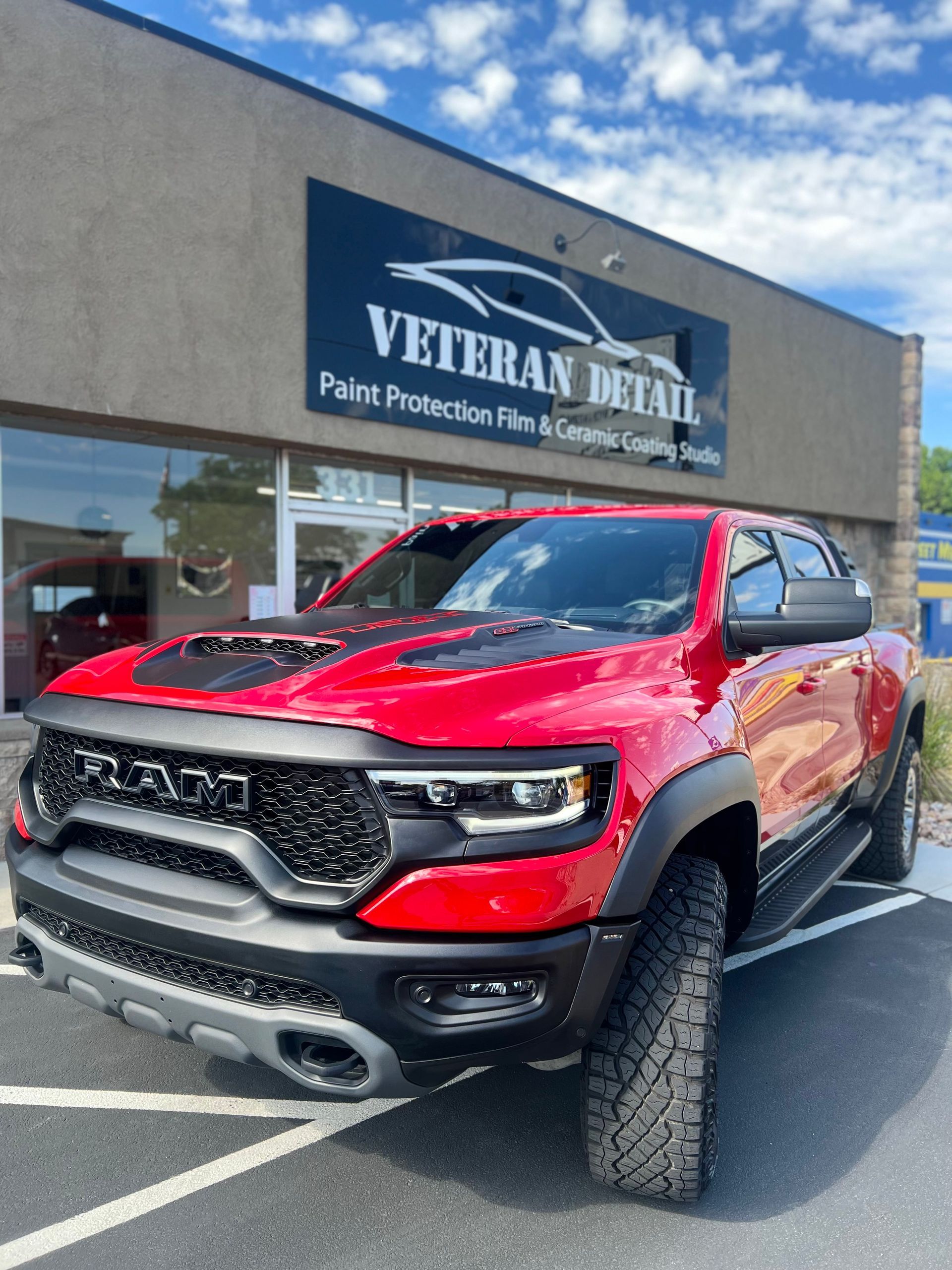 A red ram truck is parked in front of a veteran detailing shop.