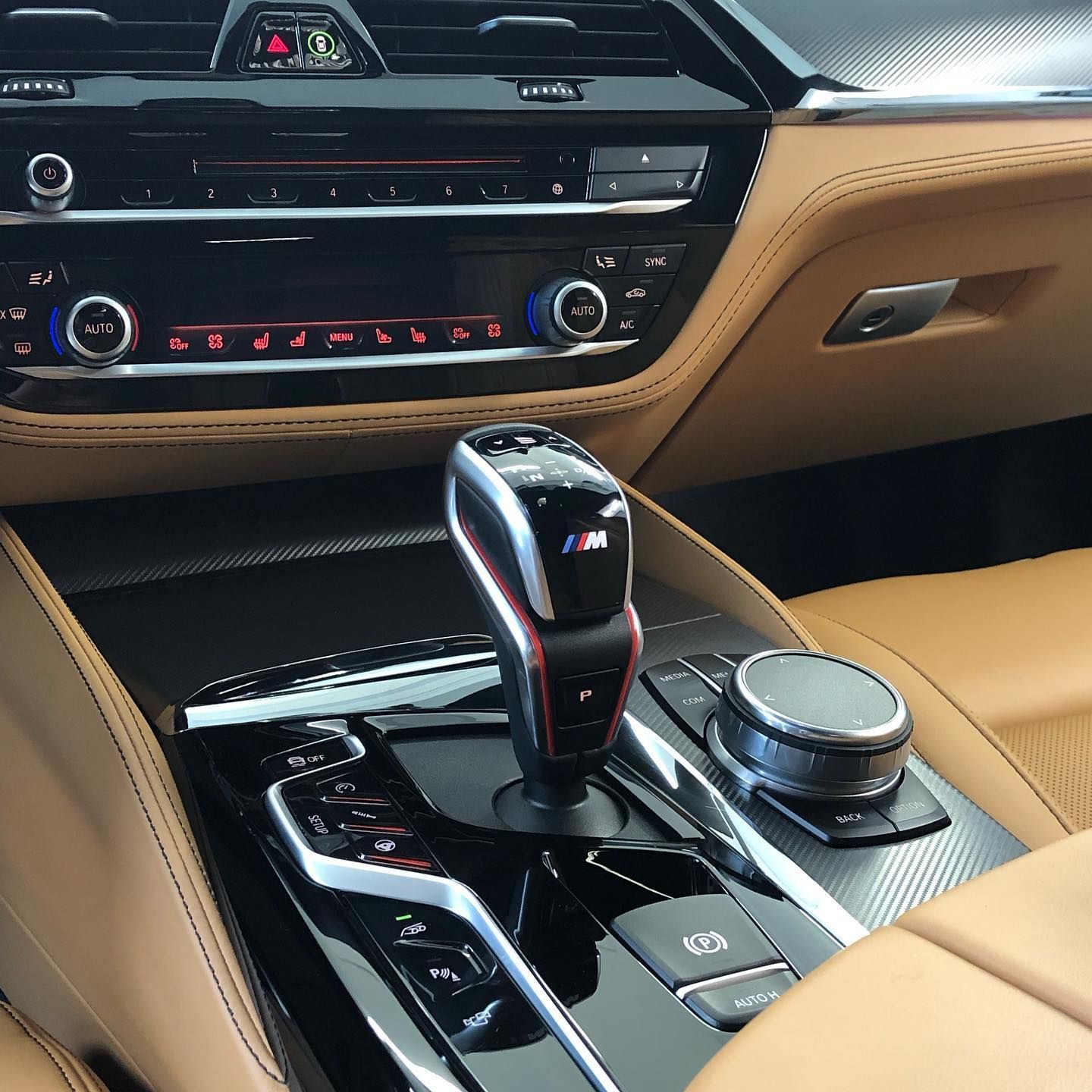 Tan leather car interior with a black gear shift, center console, and dashboard.