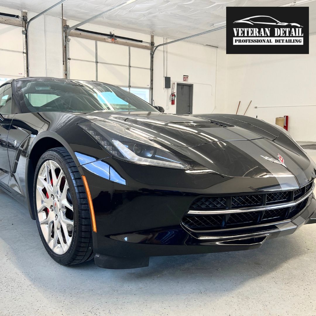 Black Corvette sports car, in a professional detailing shop, with the Veteran Detail logo.
