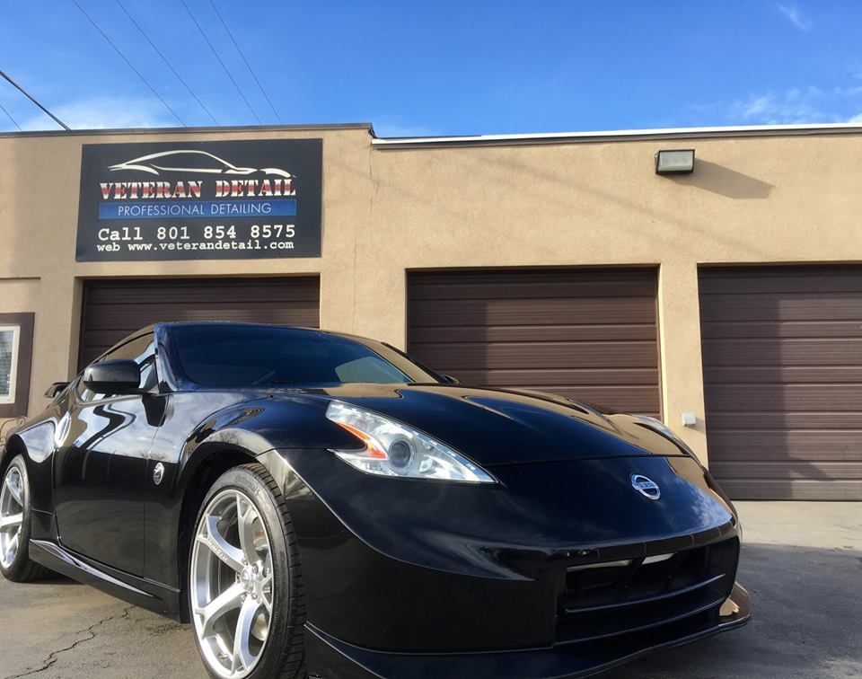 A black sports car is parked in front of a building that says veteran detail