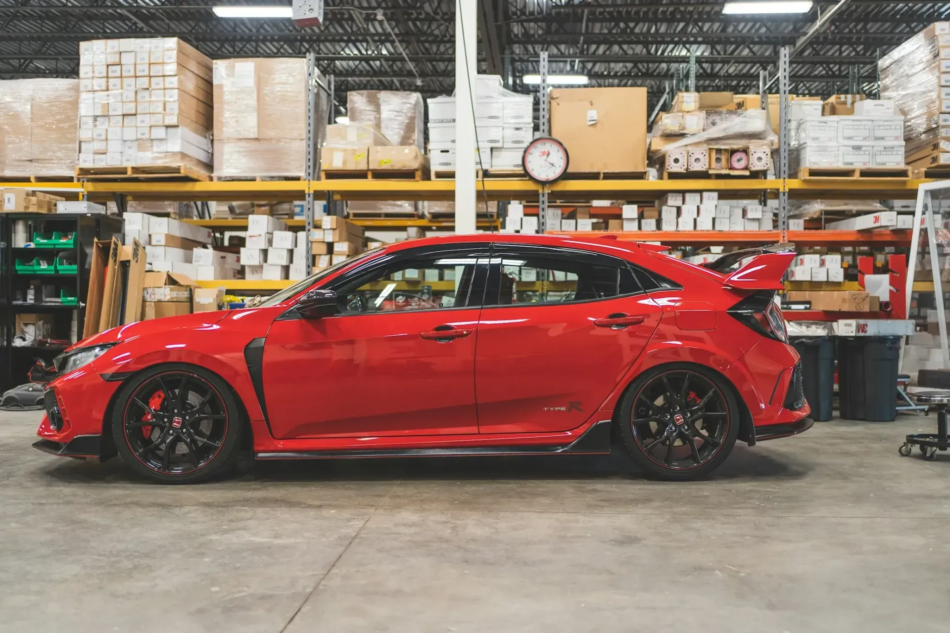 A red honda civic type r is parked in a warehouse.
