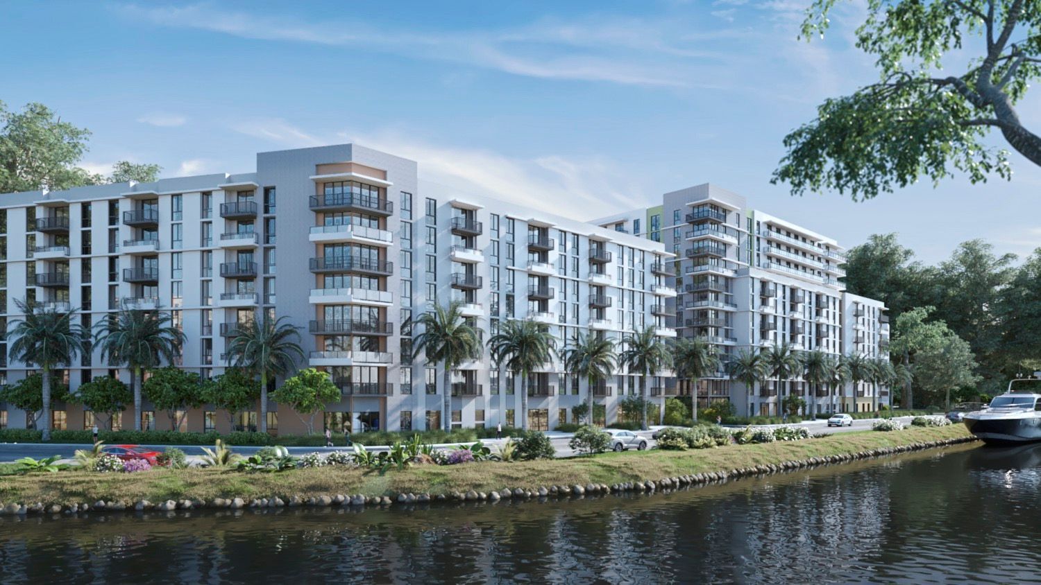 Modern waterfront apartment complex with balconies beside a canal, trees, and clear blue sky