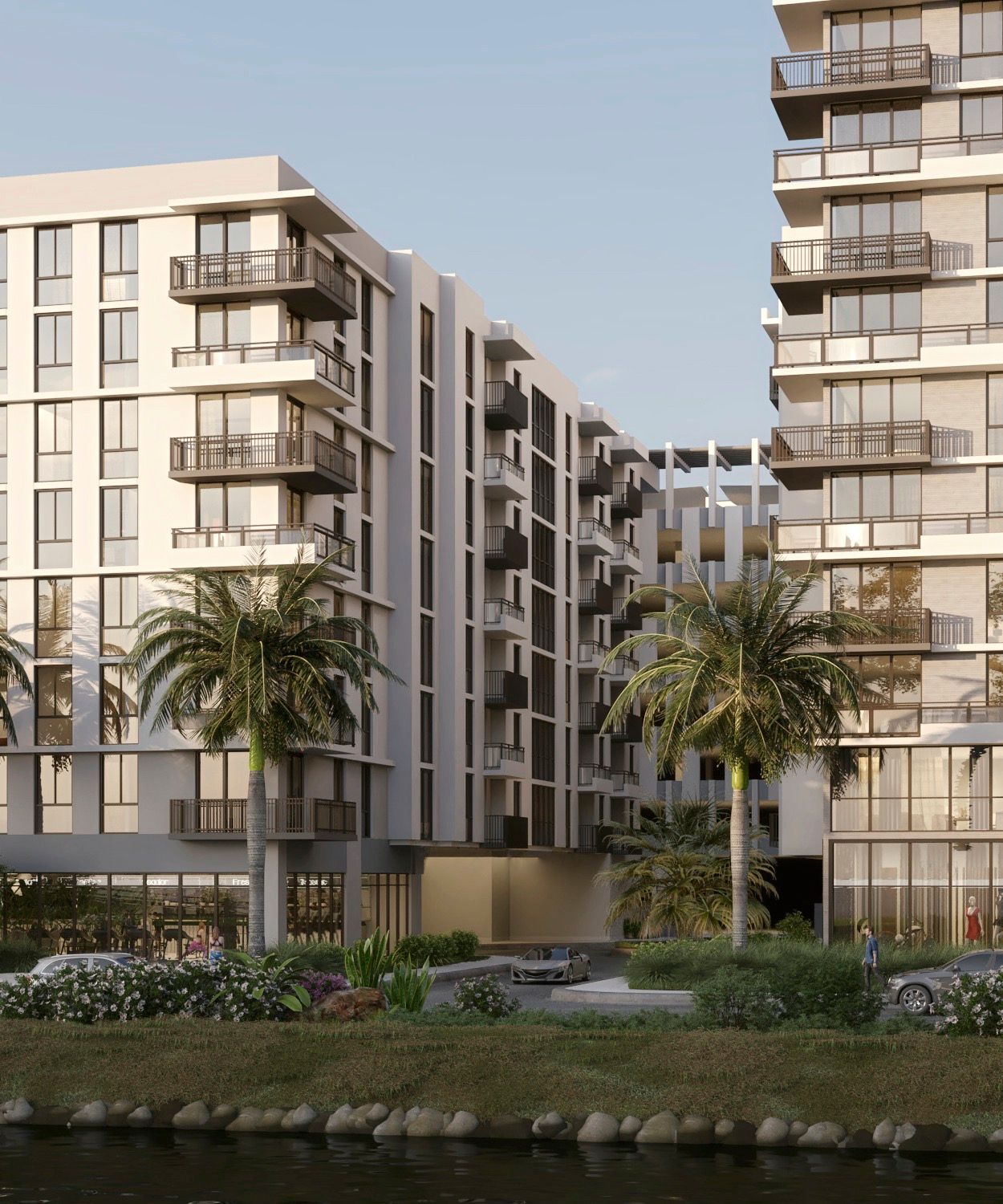 Modern apartment buildings with balconies beside a waterfront and palm trees