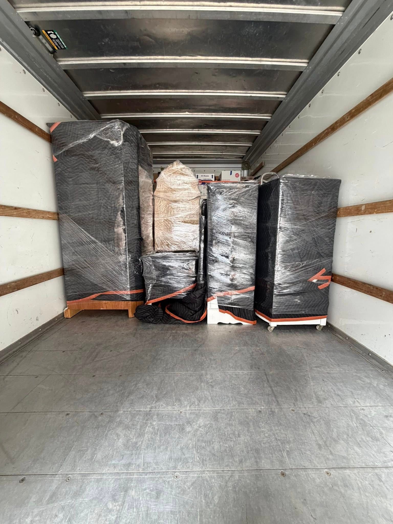 Cargo trailer interior with four wrapped pallets loaded at the back.