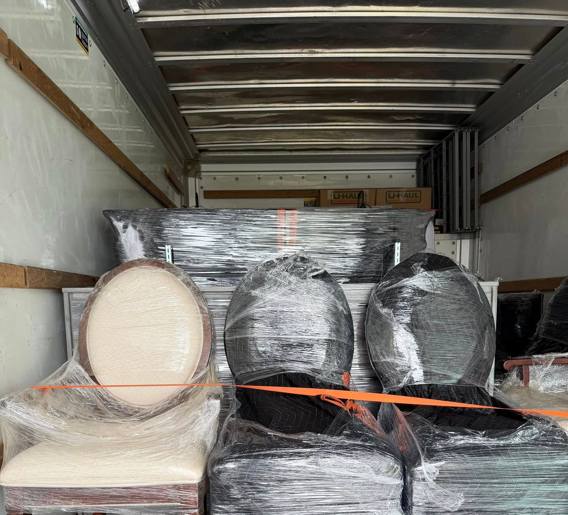 Shrink-wrapped furniture and an oval mirror loaded in a moving truck