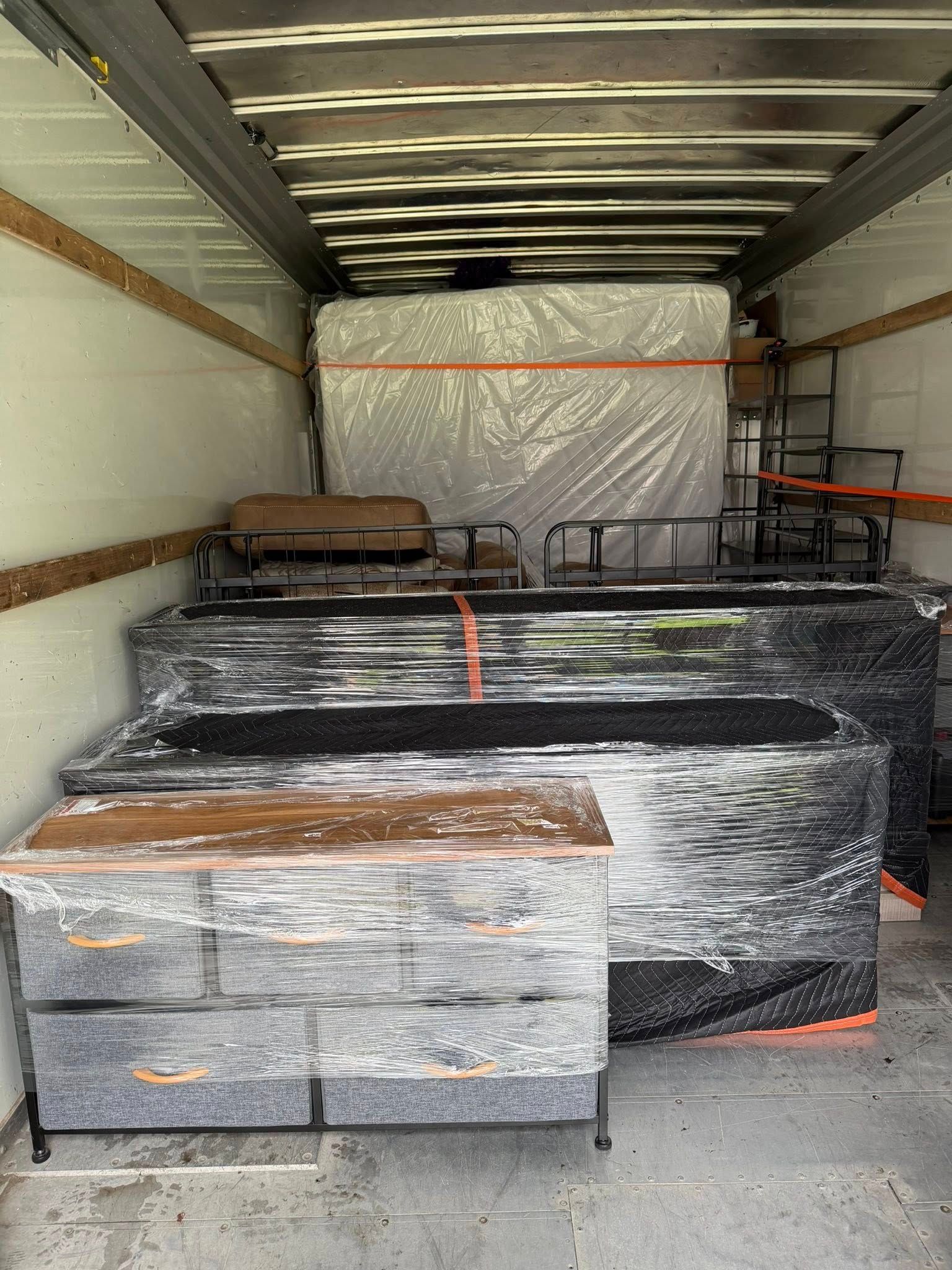 Packed moving truck with wrapped furniture and boxes secured inside.