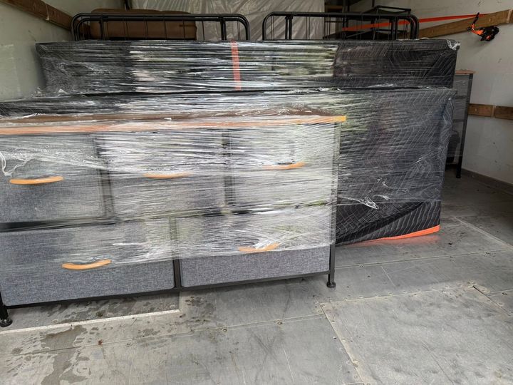 Wrapped black furniture or equipment stacked in a garage, secured with orange straps.