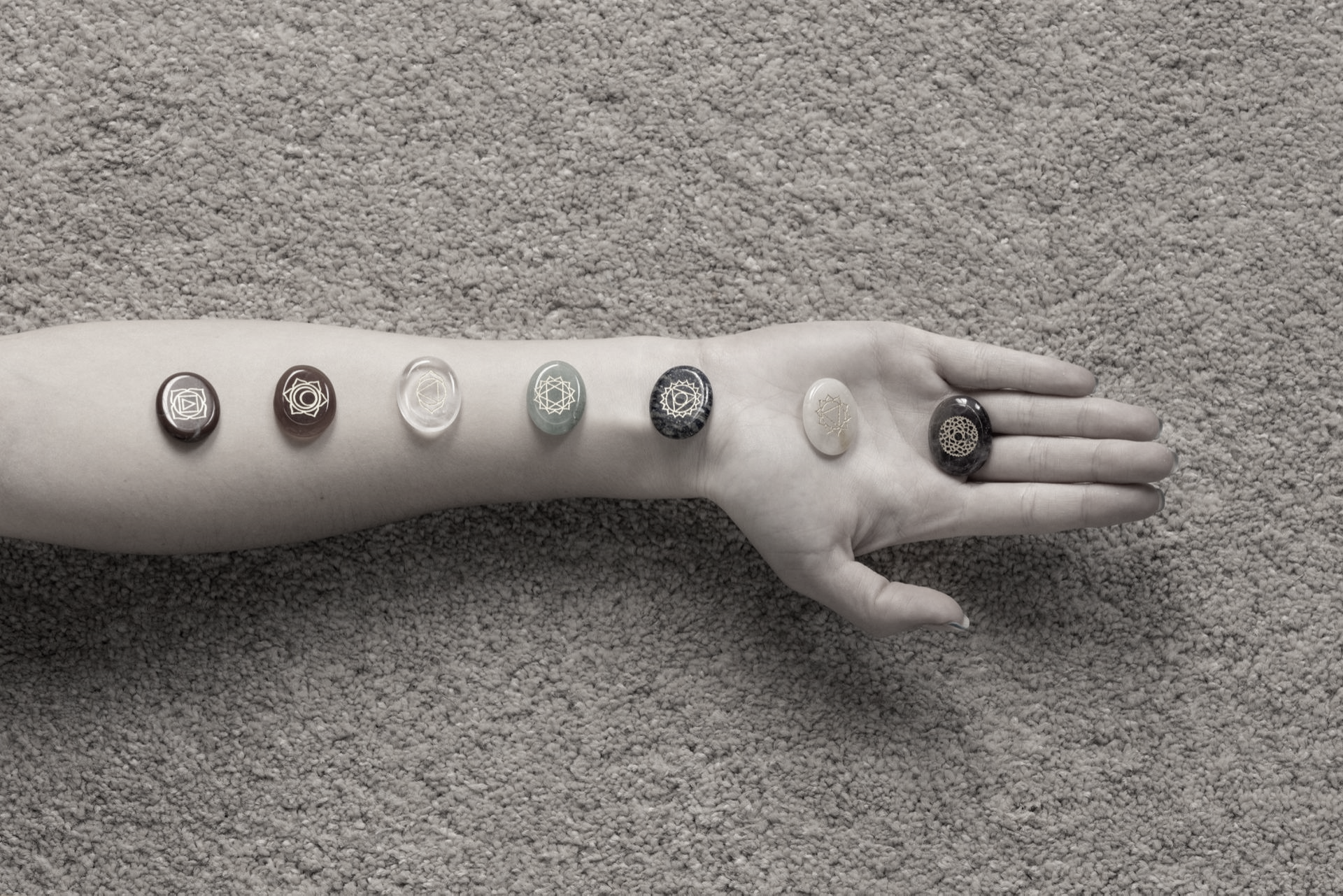 Una mano con varios objetos redondos de distintos colores y diseños colocados en el antebrazo 