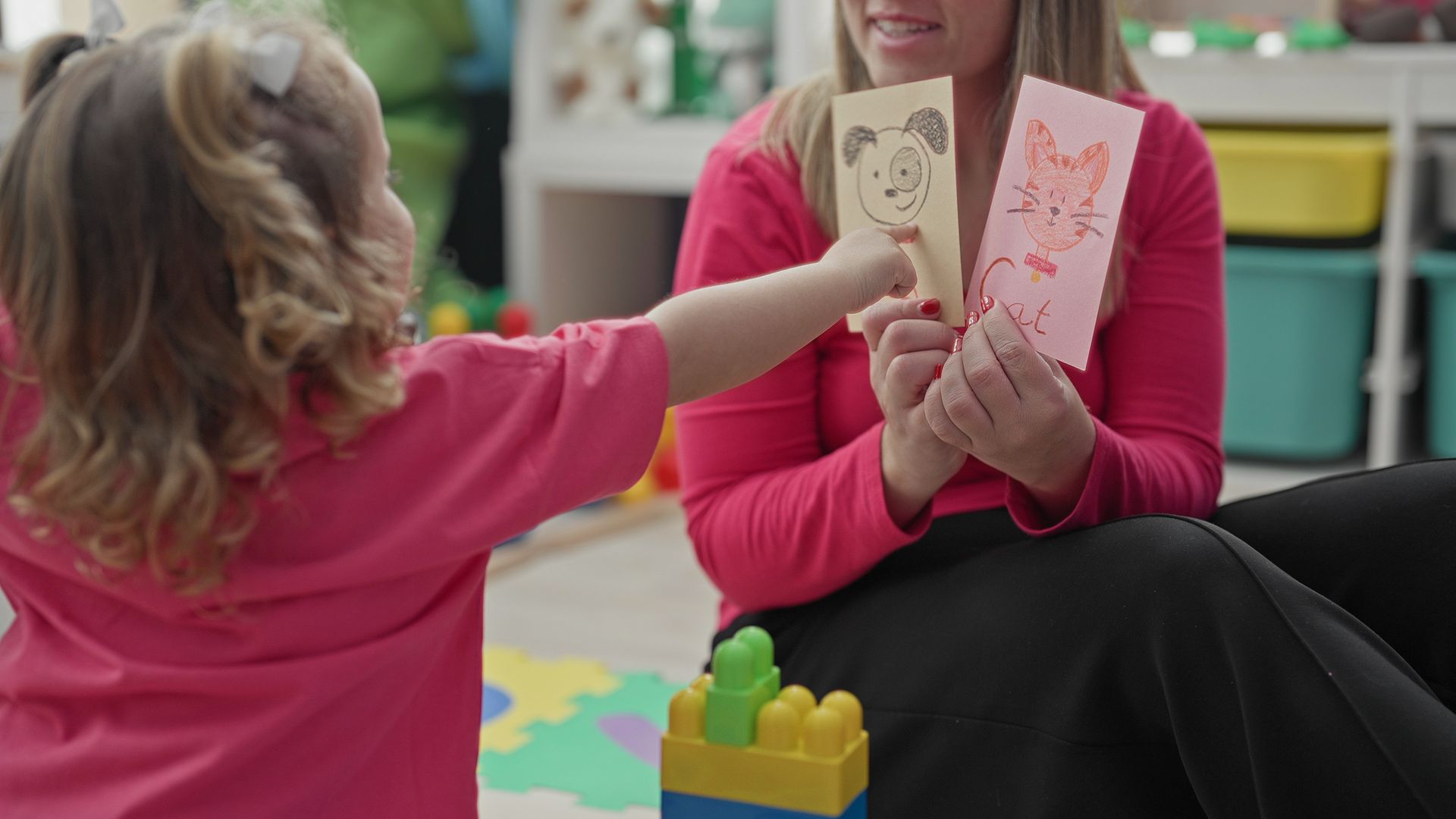 Child at an early learning center hands a flashcard to a teacher during an interactive early learnin