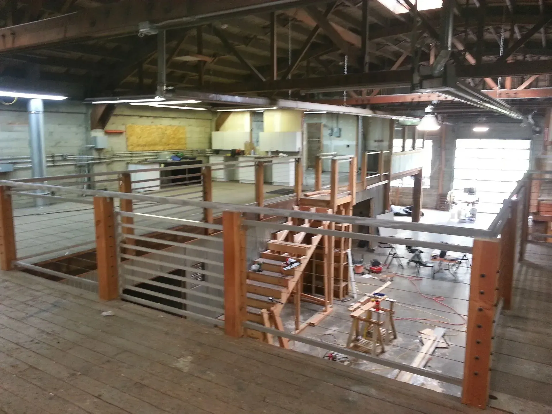 Wooden ramp with metal railings in an unfinished industrial building.