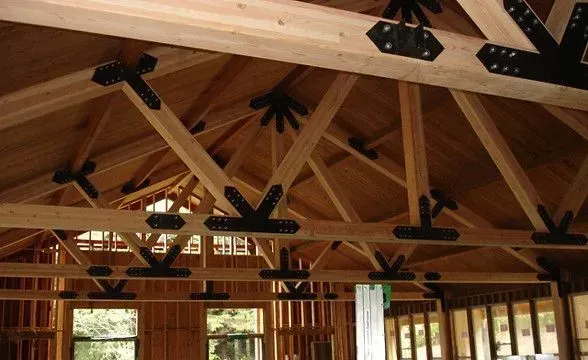 Wooden roof trusses with black metal connectors, interior view.