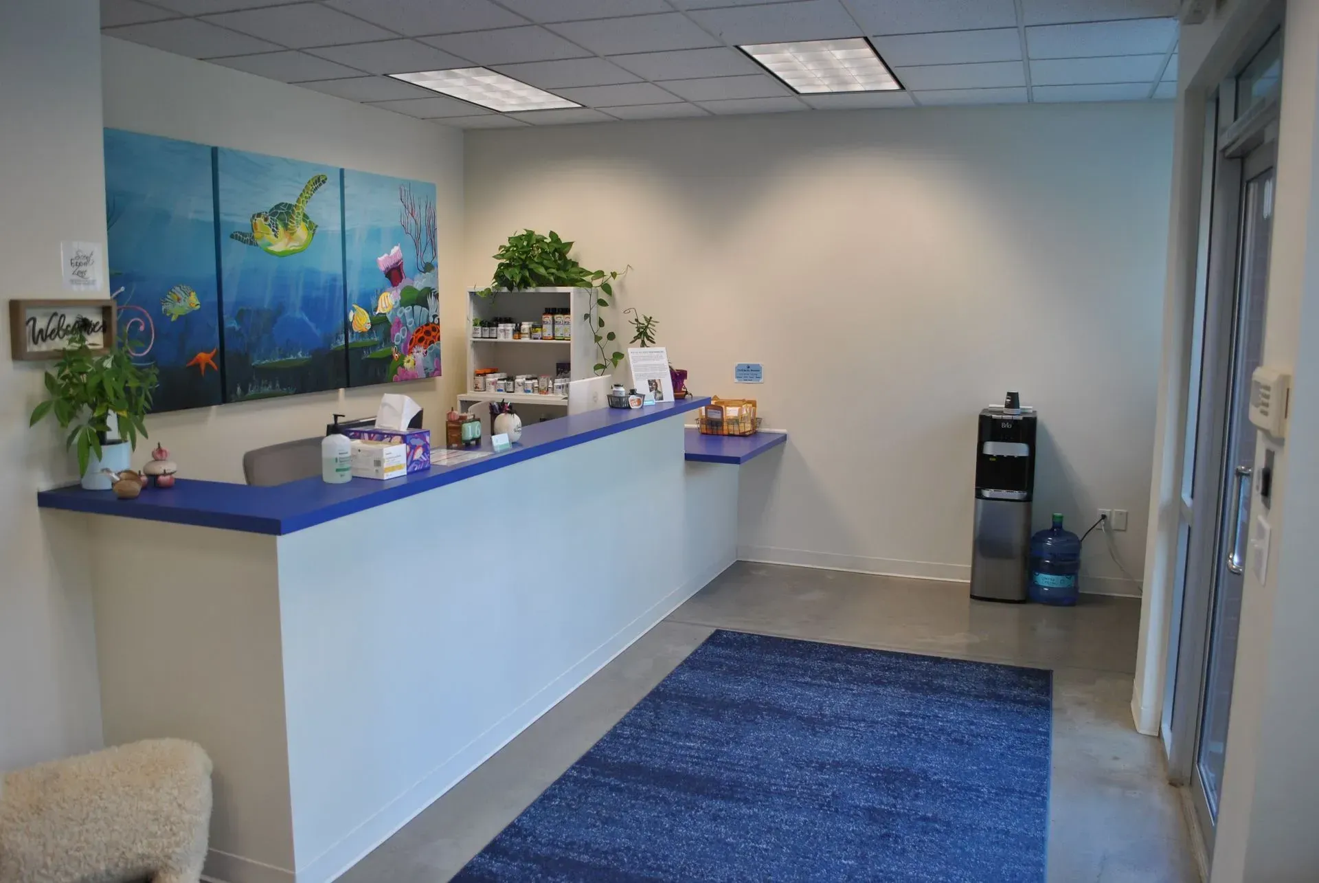 Reception area with blue accents, artwork of underwater scene, and water cooler.