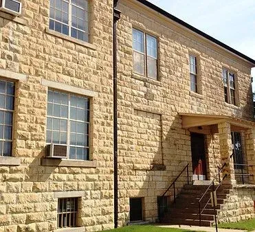 Stone building with multiple windows and a small porch entrance.