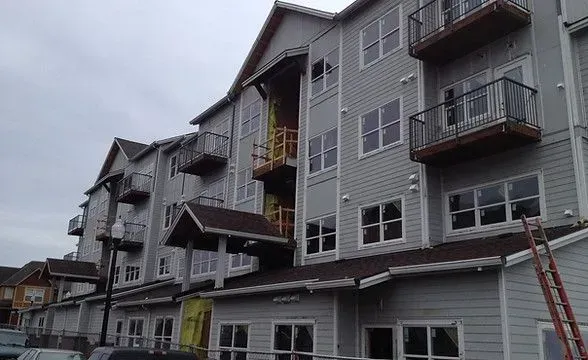 Gray multi-story apartment building with balconies and white window frames.