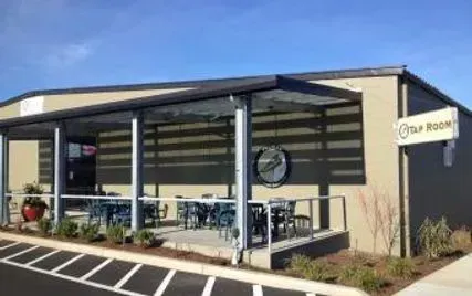 Tap Room bar with outdoor seating, tan building with a blue sky.