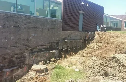 A retaining wall under construction next to a brick building.