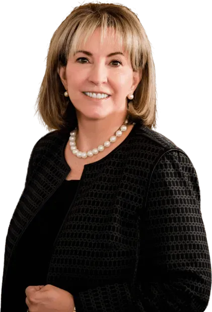 Woman smiling, wearing black jacket, pearl necklace.