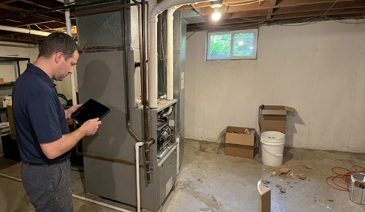 A professional HVAC technician from Spokane Heating and Cooling inspecting a residential furnace.