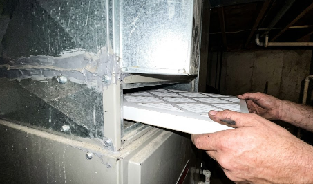 HVAC professional changing a dirty air filter with a new one during maintenance.