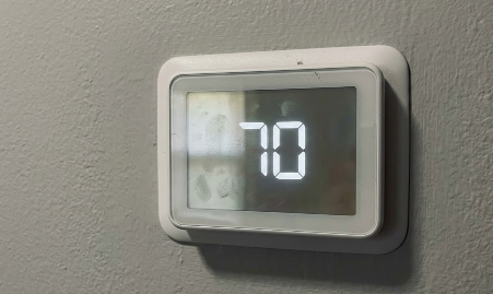 A modern smart thermostat displaying a comfortable indoor temperature.