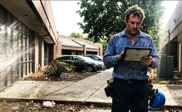 Friendly Spokane Heating and Cooling technician standing in front of a commercial office building.