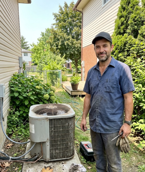 Friendly Spokane Heating and Cooling technician standing next to an outdoor AC unit.