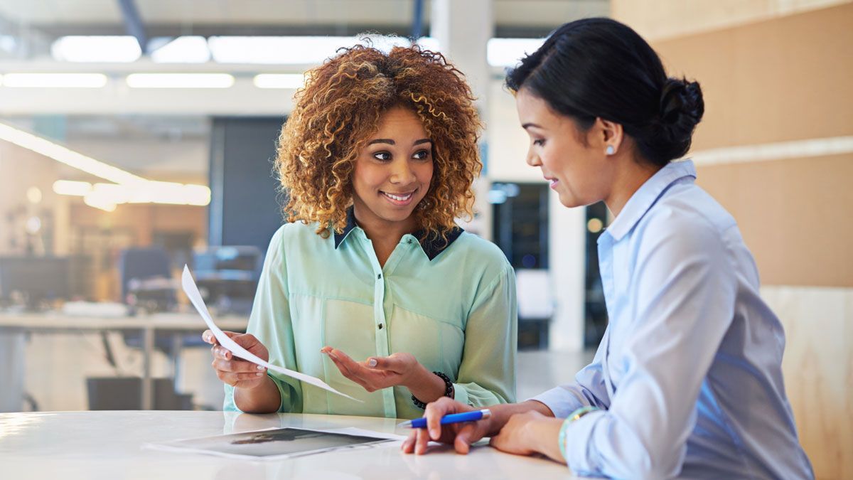 Two business professionals reviewing paperwork and discussing employee benefits