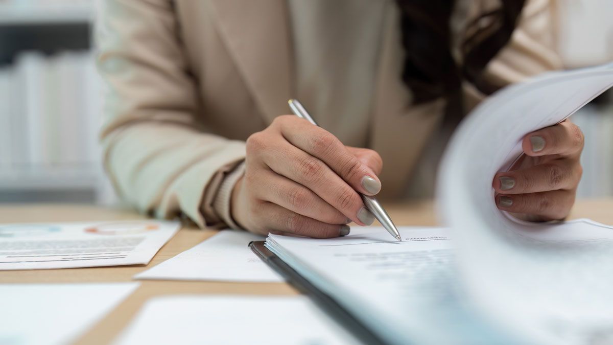 Business professional reviewing and signing documents at an office desk
