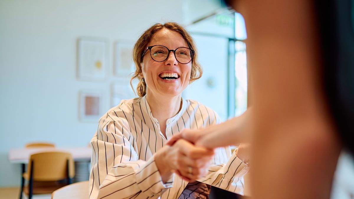 HR professional shaking hands with an employee during a workplace meeting