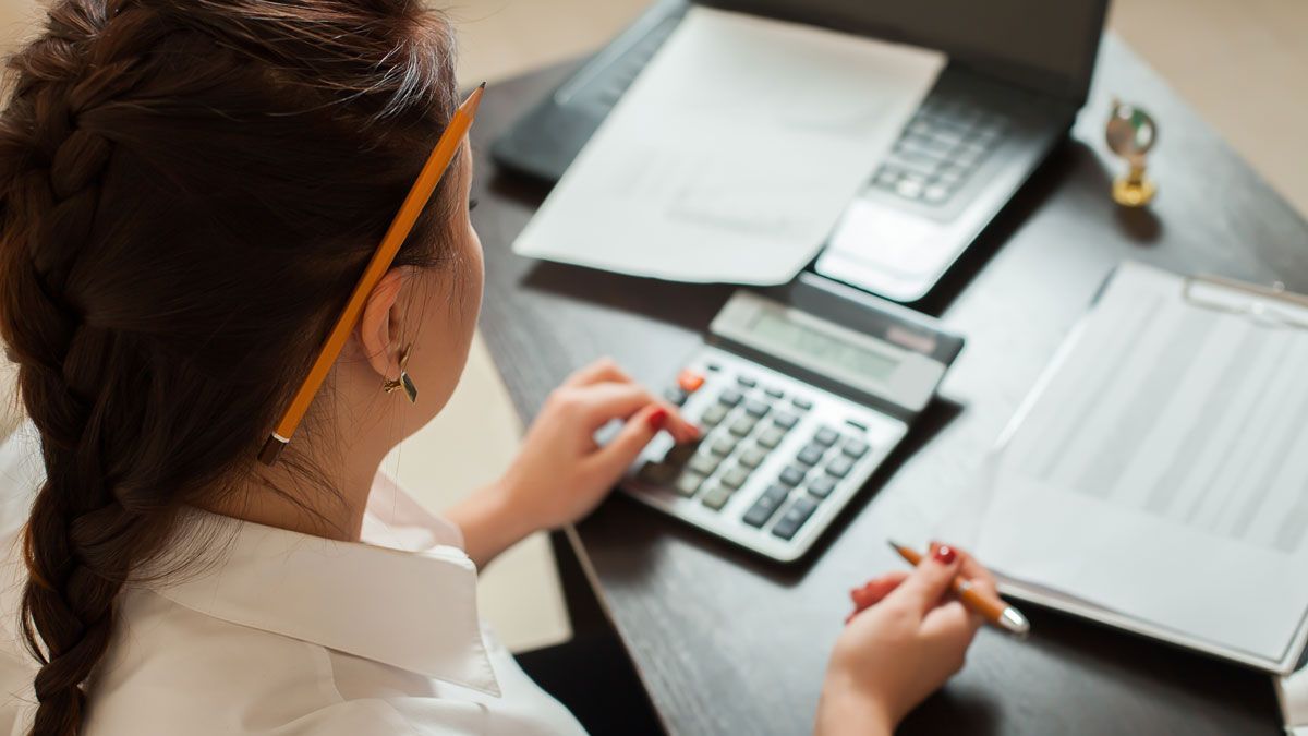 Business professional reviewing financial paperwork with a calculator and laptop